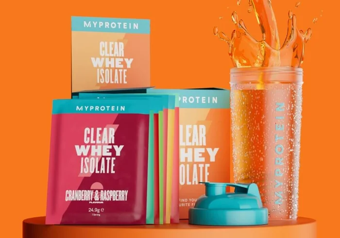 Caja de Muestras Clear Whey con varios sabores, entre ellos arándano y frambuesa y naranja y mango, junto a un shaker de la marca Myprotein.