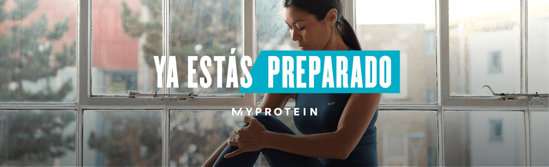 Una mujer con ropa de gimnasia MP sentada en el alféizar de una ventana mientras estira los músculos con el texto "YOU'RE READY - MY PROTEINS" superpuesto en la imagen.
