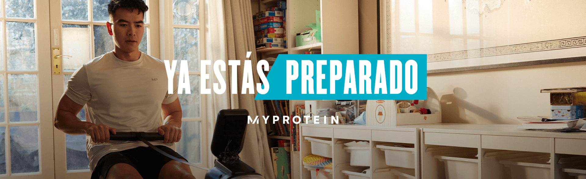 Un uomo si allena su un vogatore a casa con le parole "Sei già pronto - MY PROTEIN" sovrapposte.